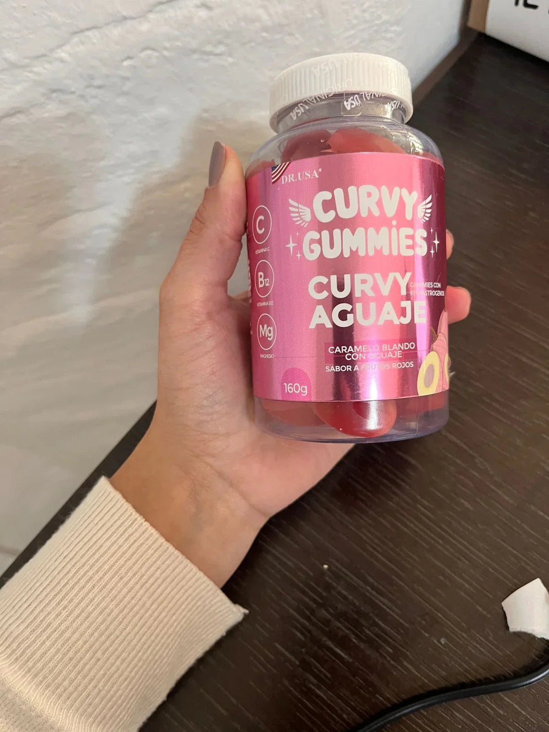 Frasco de vitaminas Curvy Gummies Aguaje con caramelo blando sabor a frutos rojos, mano sosteniéndolo